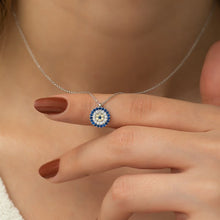 Necklace with a blue and white pendant held by a hand against a neutral background