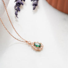 Rose gold necklace with a green gemstone pendant on a white background