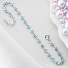 Silver bracelet with blue heart-shaped beads on a white surface