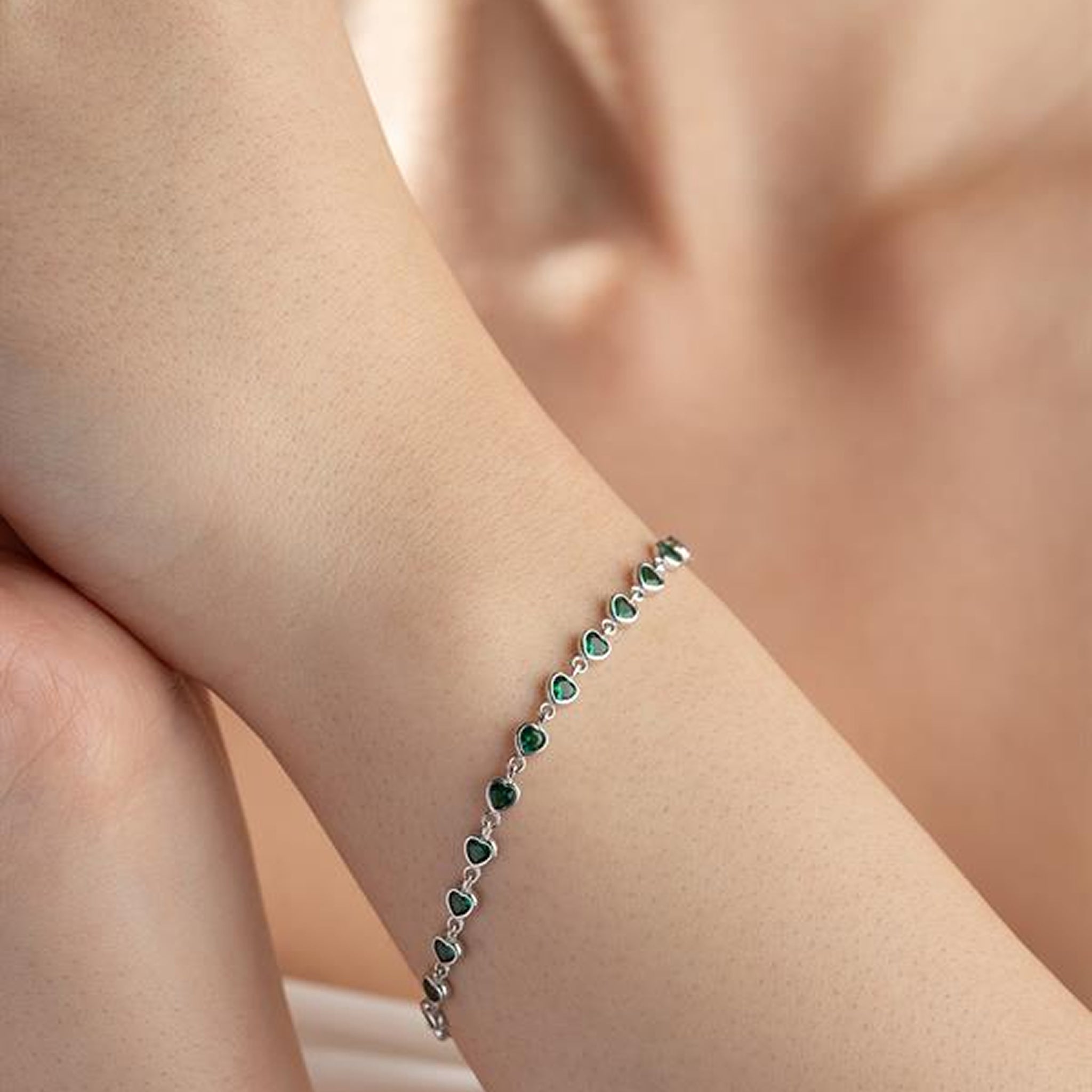 Green gemstone bracelet on a person's wrist with a soft background