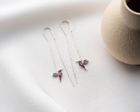 Close-up of silver hummingbird earrings with artistic details