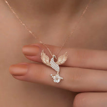 Rose gold necklace with a phoenix pendant held by a hand against a neutral background