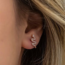 Close-up of an ear wearing a sparkling earring with blonde hair.