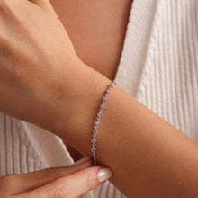 Silver bracelet on a wrist with a neutral background