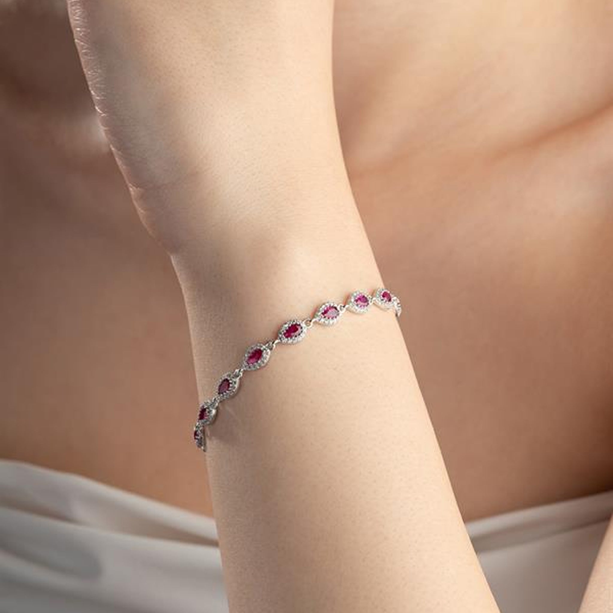Bracelet with red gemstones on a person's wrist against a neutral background