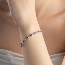 Bracelet with red gemstones on a person's wrist against a neutral background