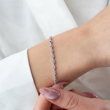 Silver bracelet with blue stones on a wrist against a white background