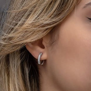Close-up of a person wearing a silver hoop earring with a blurred background