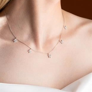 Necklace with small pendants on a person's neck against a neutral background