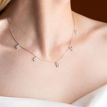 Necklace with small pendants on a person's neck against a neutral background