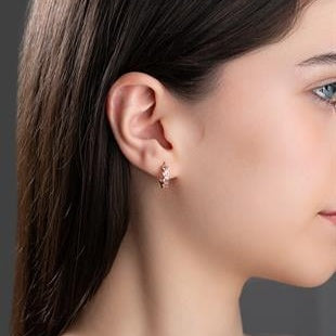 Close-up of a woman wearing a diamond earring with a dark background