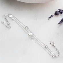 Silver bracelet with floral designs on a white surface