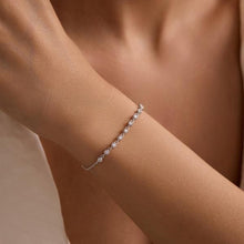 Silver bracelet on a person's wrist with a neutral background
