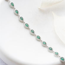 Silver bracelet with green gemstones on a white background