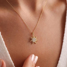 Gold necklace with a sun-shaped pendant on a person's neck