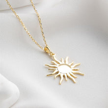 Gold sun-shaped pendant necklace on a white background