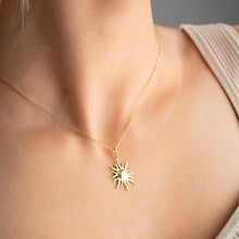 Gold necklace with a sun pendant on a person's neck against a neutral background