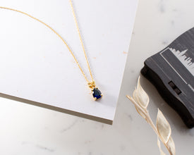 Birthstone jewelry featuring an elegant oval blue sapphire charm.
