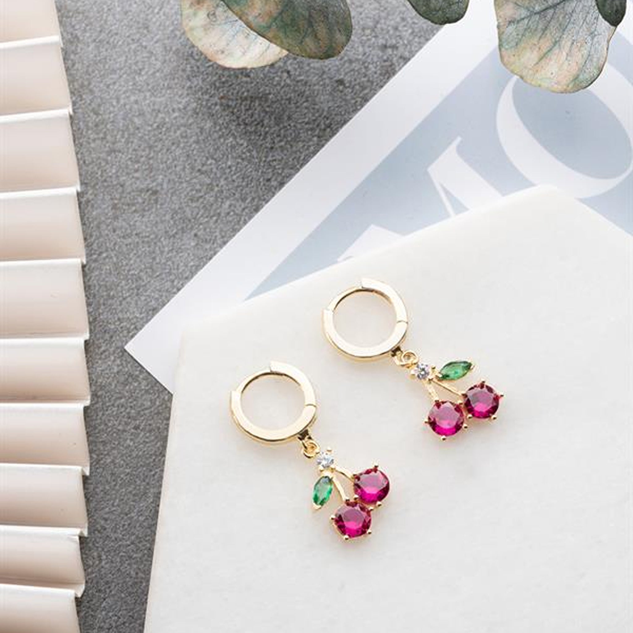 Gold earrings with gemstones on a light surface