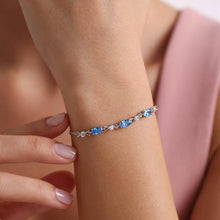 Bracelet with blue gemstones on a wrist against a soft pink background