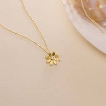 Gold necklace with a delicate flower pendant on a beige background