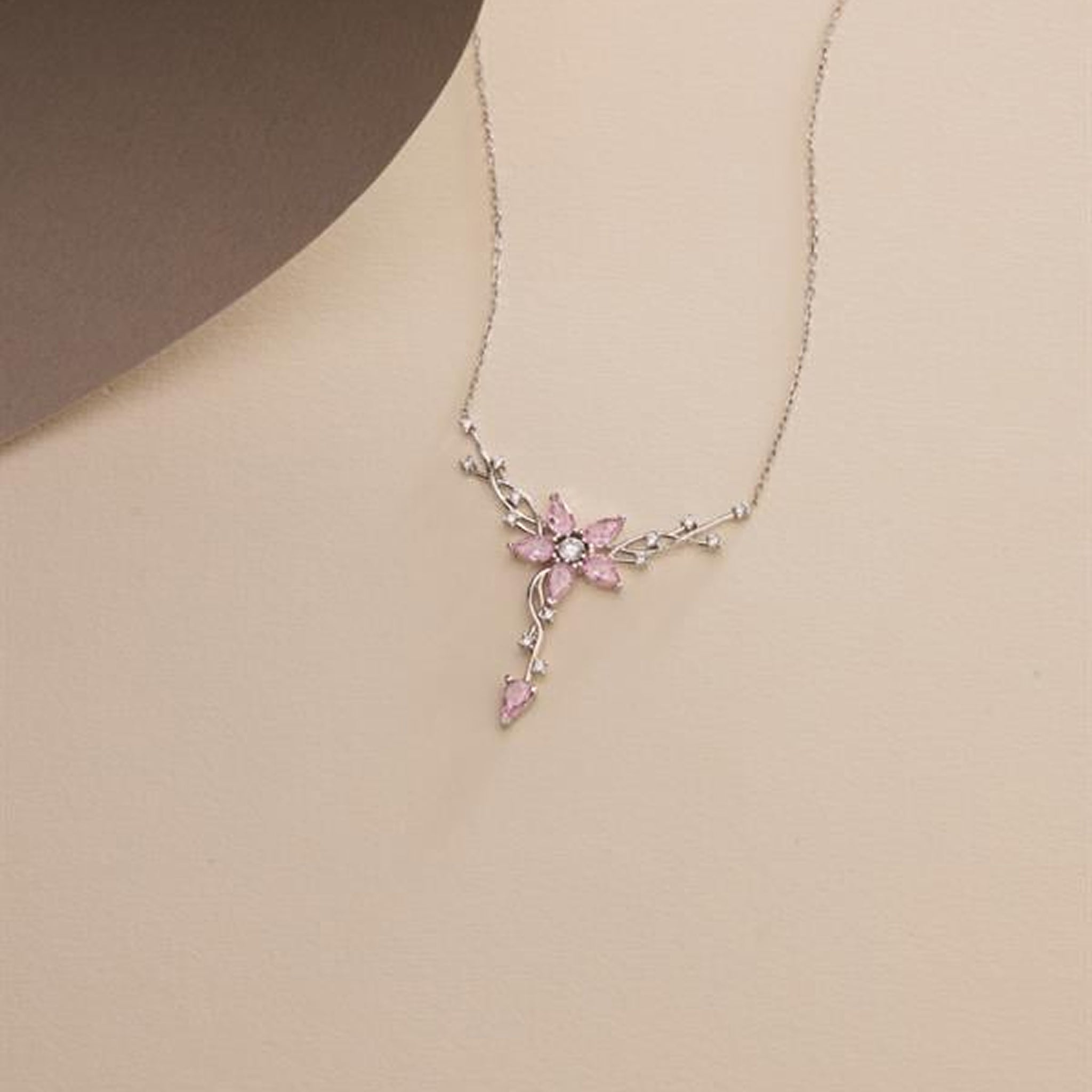 Necklace with a pink floral pendant on a beige background