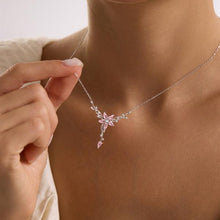 Necklace with a pink floral pendant held by a hand against a neutral background