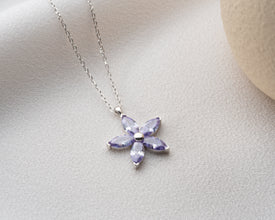 Handcrafted botanical jewelry featuring a silver flower pendant for layering.