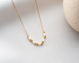 Side view of minimalist gemstone necklace on neutral backdrop