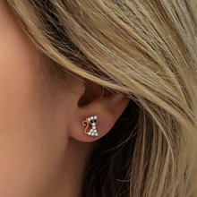 Close-up of an ear wearing a diamond-studded earring with blonde hair.