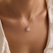 Necklace with a pink flower pendant on a person wearing a white shirt.