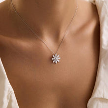 Necklace with a floral pendant on a person wearing a white shirt.