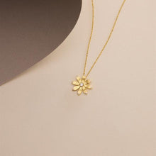 Gold necklace with a flower pendant on a beige background