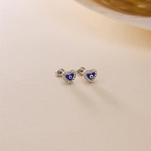 Heart-shaped earrings with blue centers on a beige background