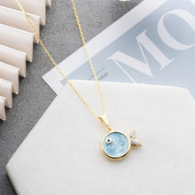 Gold necklace with a blue pendant on a magazine background