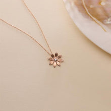 Rose gold flower-shaped necklace on a beige background