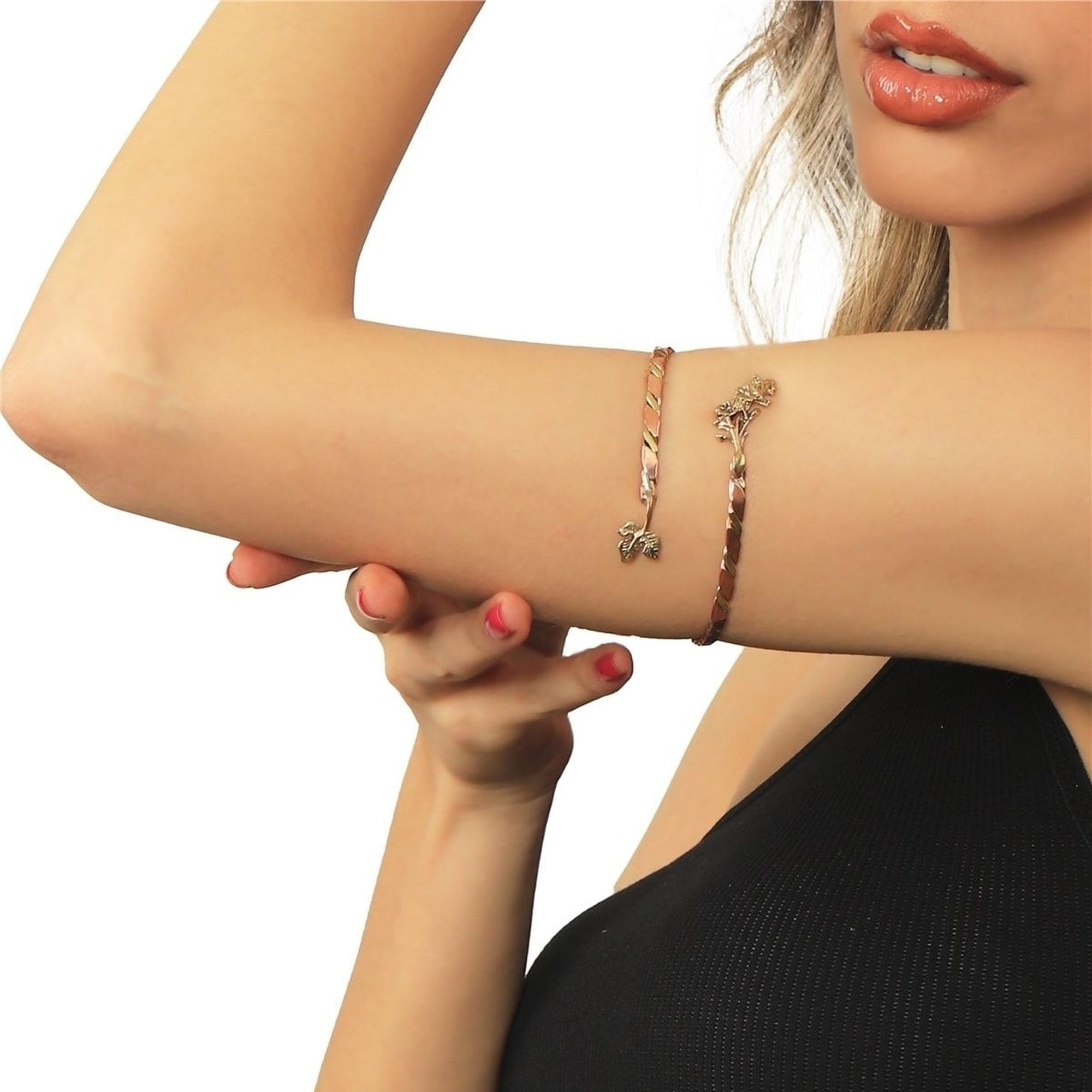 Close-up of a woman's arm wearing two bracelets on a white background