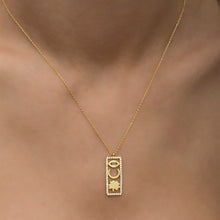 Gold necklace with a pendant featuring an eye design on a blurred background