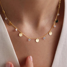 Gold necklace with round pendants and small crystals on a person wearing a light-colored top.