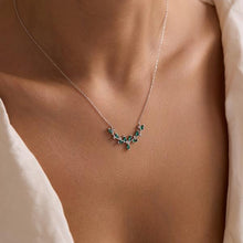 Necklace with green gemstones worn by a person, focusing on the jewelry.