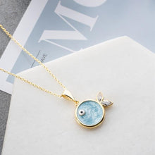Gold necklace with a blue pendant on a magazine background