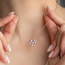 Necklace with a flower-shaped pendant held by hands against a neutral background