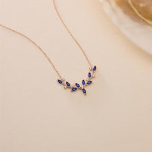 Rose gold necklace with blue gemstones on a beige background