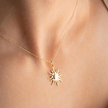 Gold necklace with a sun pendant on a person's neck