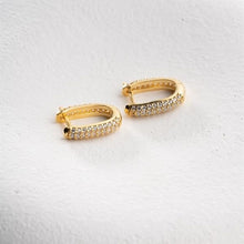 Gold hoop earrings with embedded stones on a light gray background