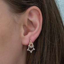 Star-shaped earring worn by a person with brown hair.