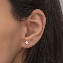 Close-up of an ear wearing a diamond earring with blurred background