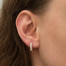 Close-up of an ear wearing a small hoop earring with a blurred background