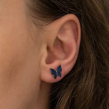 Close-up of an ear wearing a blue butterfly earring.