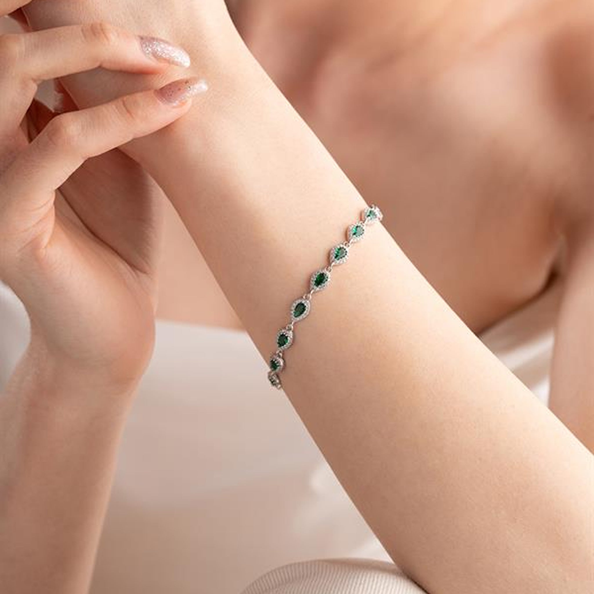 Bracelet with green gemstones on a person's wrist against a soft background